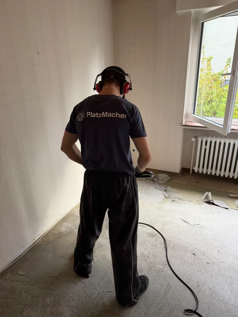 Raum nach dem Entfernen des Teppichbodens, letzte Rückenreste am Fenster werden gelöst